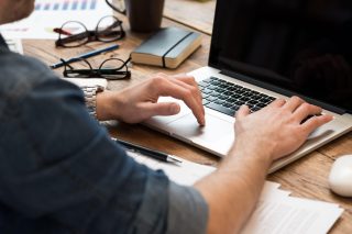 Closeup of man hands working on laptop in office