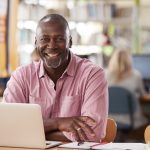 Portrait Of Mature Male Student Using Laptop In Library