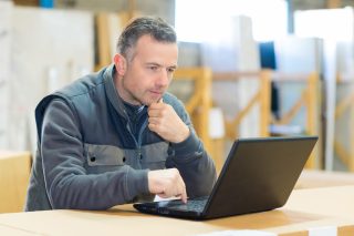 male worker looking at laptop in workshop