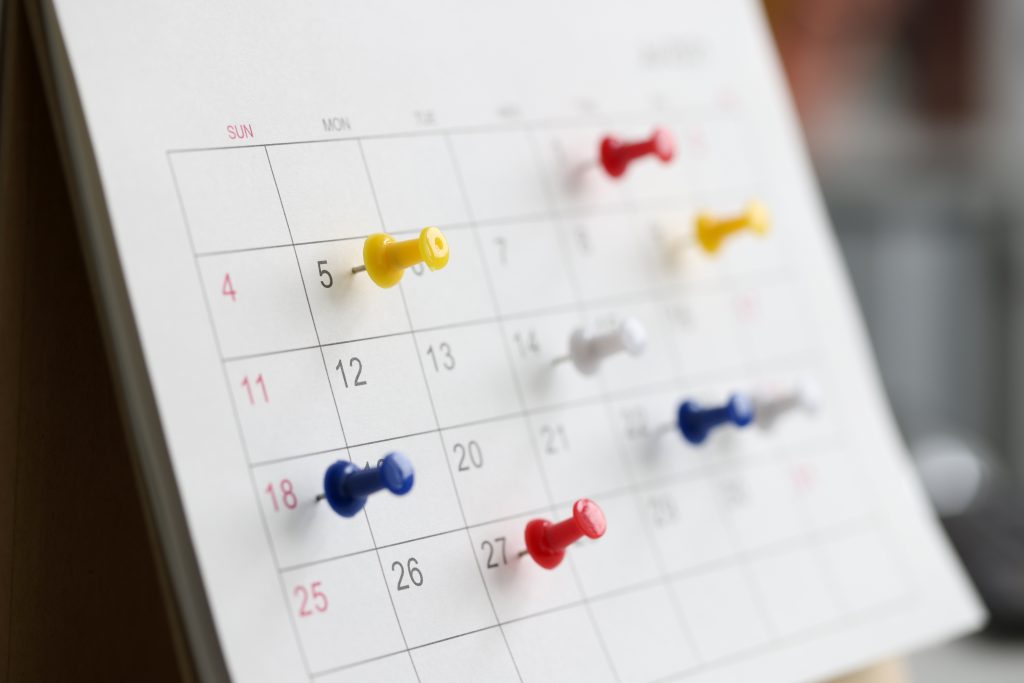 Various Color Thumb Tack Pins On Calendar As Reminder