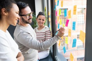 Business people meeting at office and use post it notes to share idea. Brainstorming concept. Sticky note on glass wall.