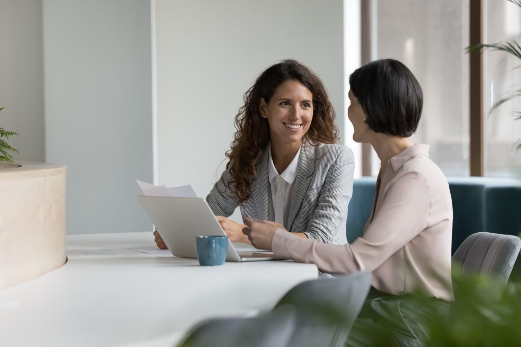 Two Positive Confident Diverse Business Colleagues Women Talking At Workplace